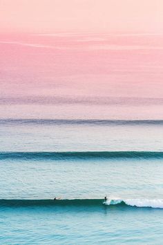 two surfers are riding the waves on their surfboards in the ocean at sunset