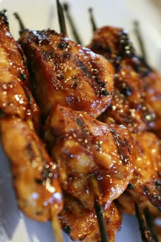 chicken skewers with sauce and seasoning on them sitting on a white plate