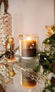 a lit candle sitting on top of a table next to flowers and other decor items