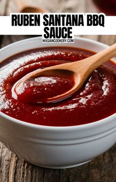 a white bowl filled with red sauce on top of a wooden table next to a spoon