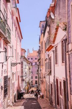 an alley way with several buildings and people walking on the sidewalk in front of them