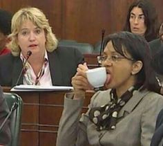 a woman drinking from a cup while sitting in a courtroom