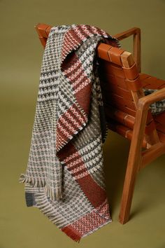 a wooden bench with a plaid blanket draped over it next to a red and white checkered scarf