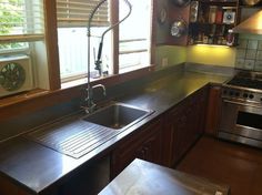 a kitchen with a sink, stove and window in the corner next to an oven