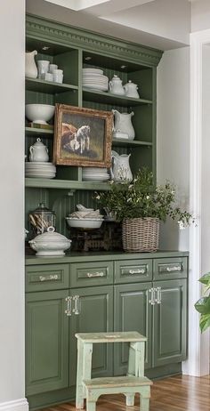 a kitchen with green cabinets and white dishes