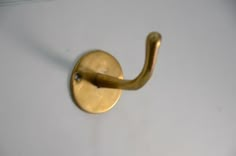 a close up of a brass hook on a white wall