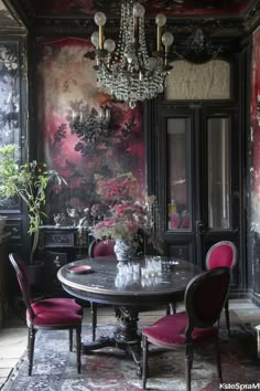 a dining room with red chairs and a chandelier hanging from the ceiling over a round table