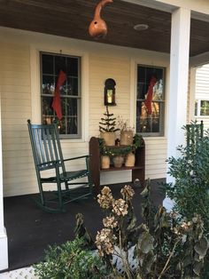 a rocking chair on the front porch of a house with potted plants and christmas decorations