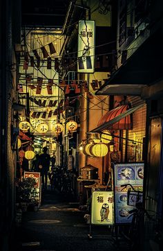 an alley way with many signs and lights hanging from the side of it at night