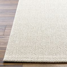 a white rug on top of a wooden floor next to a wood flooring board