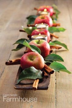 a row of apples with cinnamon sticks and leaves on them, lined up in rows