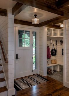 an entryway with white walls and wood flooring next to a wooden stair case