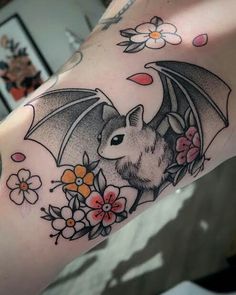 a bat tattoo on the arm with flowers