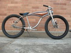 a silver bike parked next to a brick wall