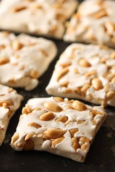 some kind of food that is on a black surface with white icing and nuts