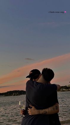 two people are hugging on the beach at sunset with a kite flying in the sky