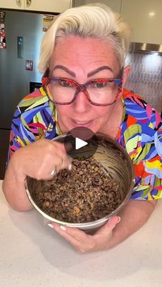 a woman with glasses is holding a bowl full of food in front of her face