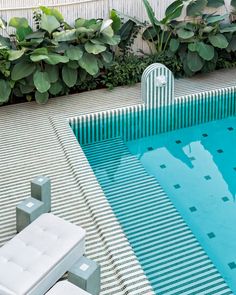 an empty swimming pool surrounded by greenery and white lounge chairs in front of it