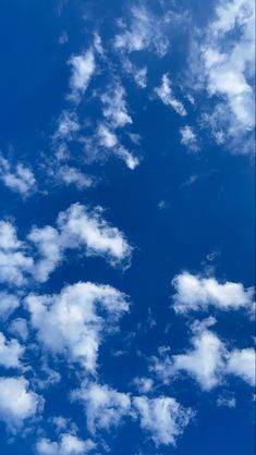 the airplane is flying high in the blue sky with white clouds above it and below