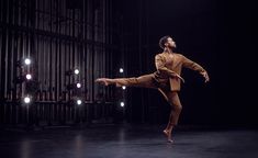 a male dancer in an orange suit is doing a trick