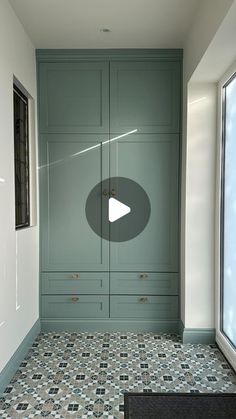 an empty room with green cabinets and tile flooring in front of a large window