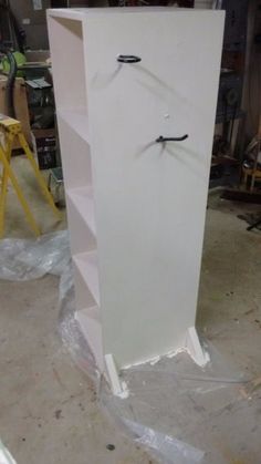 a tall white cabinet sitting inside of a room