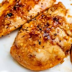 two pieces of chicken on a plate with sauce and seasoning sprinkles