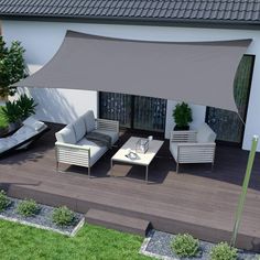 an outdoor patio with white furniture and a gray awning over the top of it