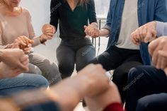 a group of people sitting around each other holding hands