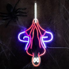 a neon sign with a spider hanging from it's side