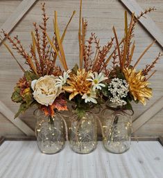 three vases with flowers in them sitting on a table