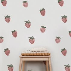 a small stool in front of a wall with strawberries on it