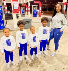 a group of children standing next to each other in front of a gas station sign