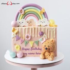 a birthday cake with a teddy bear and rainbow decoration on it's side, in front of a white background