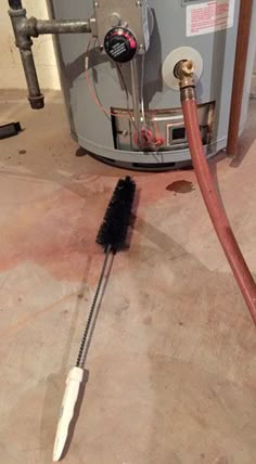 a brush is laying on the floor next to a water heater