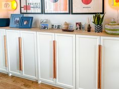 there are pictures on the wall above the cabinets in this living room, along with other decorations