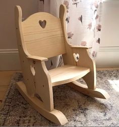 a wooden rocking chair sitting on top of a rug in front of a window with curtains