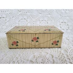 an old wooden box with roses painted on the lid and sides sitting on a lace doily