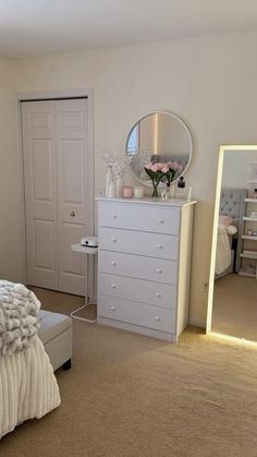 a bedroom with a bed, dresser and large mirror in it's center area