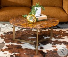 a living room with a couch, table and cowhide rugs on the floor