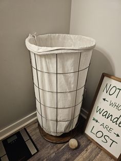 a white basket sitting on top of a wooden floor next to a sign that says not who wander are lost