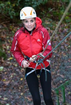 a woman in red jacket and white helmet standing on rope