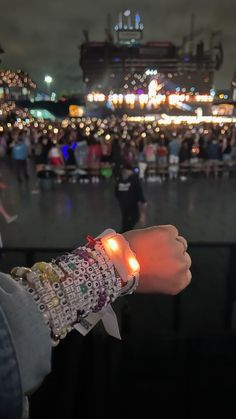 a person wearing bracelets with lights on their wrist in front of a large crowd