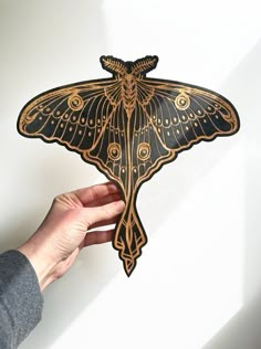 a person holding up a paper cut out of a butterfly with intricate designs on it's wings