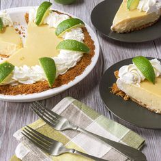 three slices of cheesecake with limes and whipped cream on top, sitting next to each other