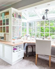 a home office with lots of windows and white furniture