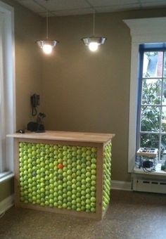 a counter made out of tennis balls in the corner of a room with two windows