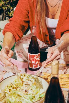 a woman sitting at a table with food and wine