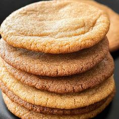 a stack of cookies sitting on top of a black plate next to a wooden spoon