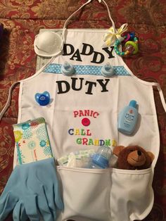 an apron that says, daddy duty with baby items in it and a teddy bear